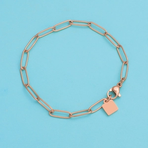 Detail of rose gold paperclip chain bracelet with a square charm and lobster clasp