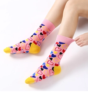 Gros plan de chaussettes roses avec motifs de cœurs colorés, pointe et revers jaunes