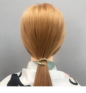 Detail of a minimalist gold geometric metal ponytail hair cuff worn on a low ponytail