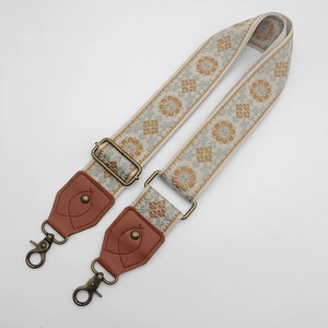 Detail of floral embroidery on adjustable canvas bag strap with bronze metal buckle