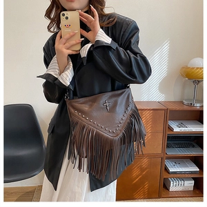Détail du sac bandoulière marron foncé avec rivets métalliques, croix argent et franges