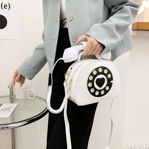 Creative white telephone-shaped crossbody bag shown on a model in a stylish suit
