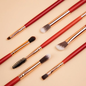 8-piece professional eye makeup brush set with red handles and gold ferrules on beige