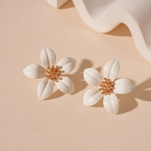 Close-up of white five-petal flower stud earrings with golden center on pink background