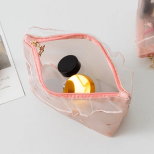 Detail of pink mesh makeup bag featuring star zipper, lace trim, and dot pattern texture