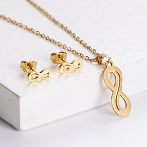 Minimalist gold infinity jewelry set featuring pendant necklace and stud earrings on wood