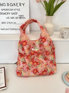 Floral canvas shoulder bag with orange and pink flower patterns in a lifestyle setting