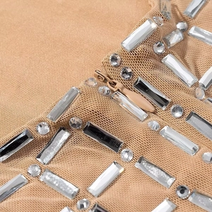 Detailaufnahme von beigem Strickstoff mit silbernen Strasssteinen und einem Metallreißverschluss