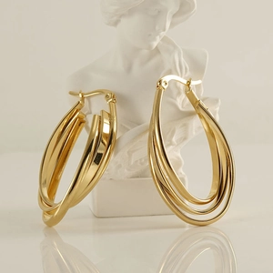 Detail of 18k gold plated multi-layered intertwined hoop earrings on a plaster statue
