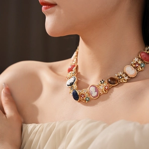 Close-up of vintage gold necklace featuring colorful cameo portraits and floral rhinestones