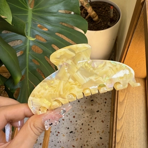 Detail of a large pearlescent yellow marble acetate hair claw with high-gloss finish