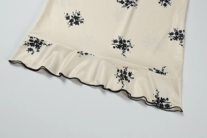 Detailed close-up of floral print dress hem with elegant black ruffled edge trim