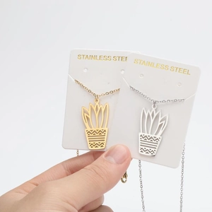 Detail of stainless steel cactus pendant necklace in gold and silver with engraved patterns