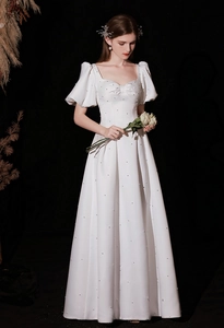 Detail of square neckline and puff sleeves on white satin dress with pearl accents
