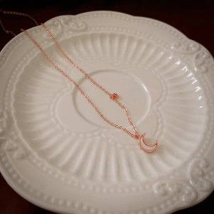 Détail du collier croissant de lune doré rose avec incrustation en nacre blanche