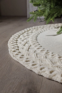 Close-up of white knitted Christmas tree skirt with thick diamond cable stitch patterns