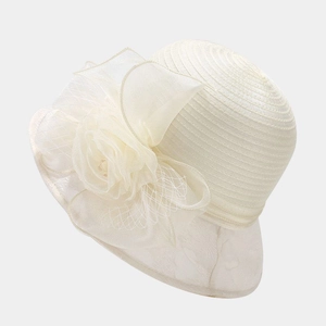 Detailed view of cream organza floral decoration and spiral woven texture on lady's dress hat