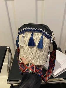 Detail of straw bucket bag with black PU leather trim and colorful geometric strap