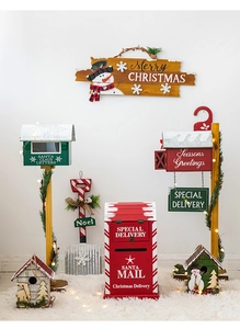 Close-up of wooden Christmas mailbox and birdhouse decor with festive pine and lights