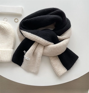 Detail of chunky knit black and white scarf featuring YOUR VOICE textile label