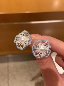 Detail of flower earrings with blue bead hollow design and white pearl center