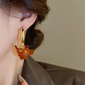 Close-up of vintage amber flower drop earrings with golden hoops on model's ear