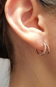 Macro shot of rose gold double hoop earrings worn by a model in a minimalist style