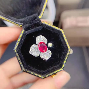Macro shot of silver ring with three diamond petals and a large oval red gemstone