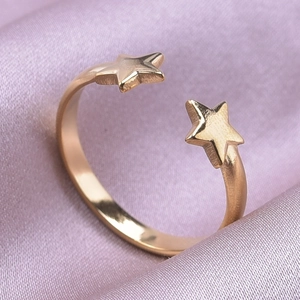 Macro detail of adjustable gold star ring on elegant purple silk fabric background