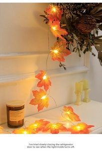 Detail of warm yellow LED maple leaf string lights draped over a cozy home fireplace