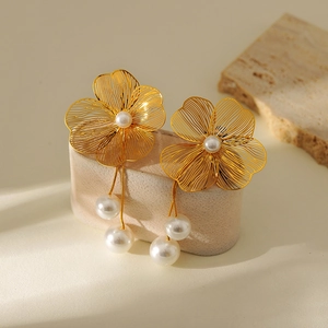 Detailed view of gold flower earrings featuring elegant hanging pearl tassels