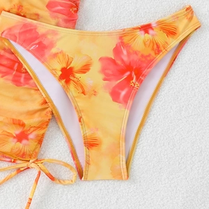 Detail of orange bikini bottom with tropical red hibiscus floral print on plush background