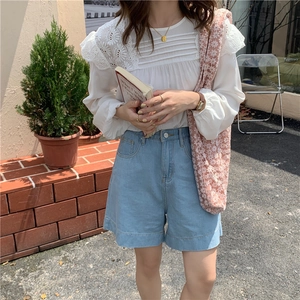 Floral lace shoulder bag paired with white lace shirt and denim shorts in a street setting