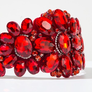 Macro detail of Baroque headband featuring large red oval gemstones and crystal embellishments