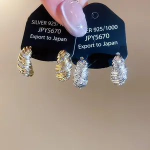 Macro shot of 925 silver screw texture earrings with inlaid crystals in gold and silver