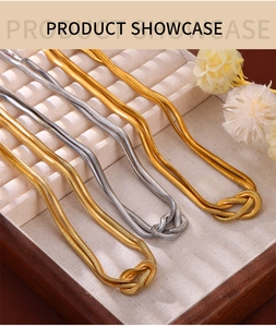 Detailed view of layered gold and silver snake bone chains with knot design in jewelry box