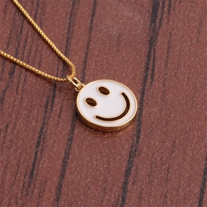 Elegant gold-plated smile face necklace with white enamel pendant on a wooden background