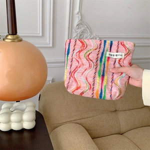 Close-up of pink knitted cosmetic bag featuring colorful wavy stripes and logo detail