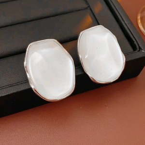 Detail of white oval resin earrings with silver metal edges on black leather display