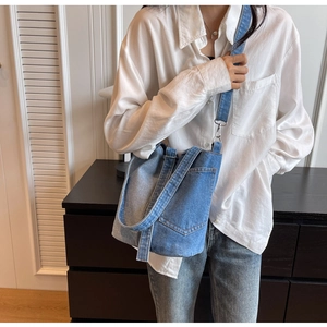 Detail of vintage denim bucket bag featuring adjustable straps and front pocket on model