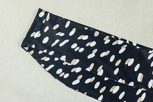 Detail of silky black fabric featuring white and beige pebble print and fine stitching