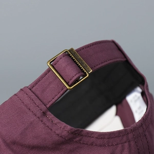 Close-up view of the adjustable brass buckle on a burgundy washed cotton baseball cap