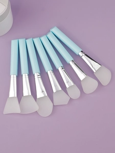 Set of 7 blue silicone face mask brushes with silver ferrules on purple background