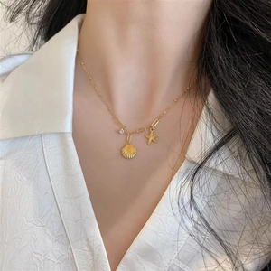 Collier en acier titane doré avec pendentifs étoile de mer et coquillage sur un mannequin