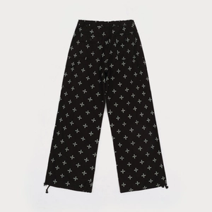 Detail of black baggy pants featuring white star pattern and adjustable drawstring cuffs