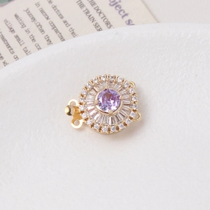 Macro detail of a 14K gold-plated flower clasp with purple gemstone and zircon inlay