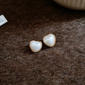 Gros plan détaillé de boucles d'oreilles cœur en perle avec bordure dorée sur tissu