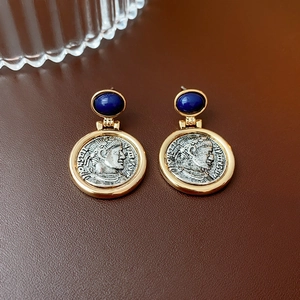 Detail of vintage coin earrings featuring a blue gem inlay and embossed portrait design