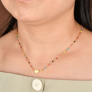Gros plan d'un collier pendentif cœur doré avec des perles multicolores sur un mannequin