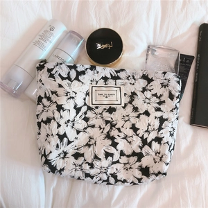 Detail of floral print makeup bag with vintage woven label and smooth zipper closure